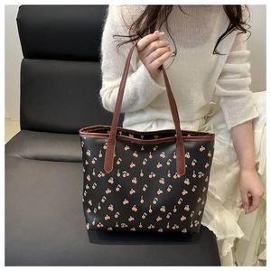Détail du sac cabas noir avec imprimé cerises et poignées marron contrastées élégantes