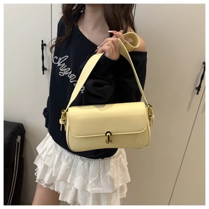 Detail of a creamy yellow faux leather shoulder bag featuring a golden twist lock closure