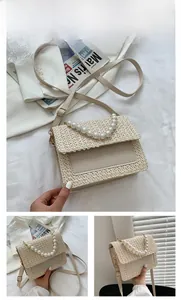 Detail of woven straw handbag with faux pearl handle and adjustable leather shoulder strap