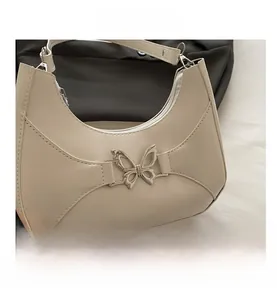 Détail du sac demi-lune crème avec boucle papillon métallique et texture en similicuir