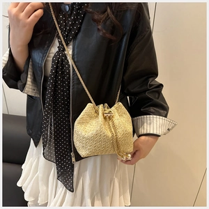 Close-up of beige woven bucket bag with gold chain strap and pearl drawstring detail