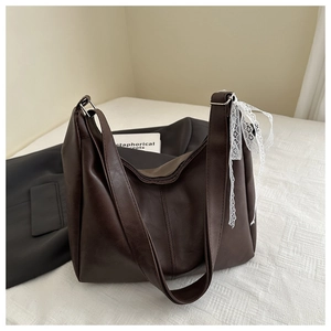 Detail of dark brown faux leather tote bag featuring a white lace bow accent decoration