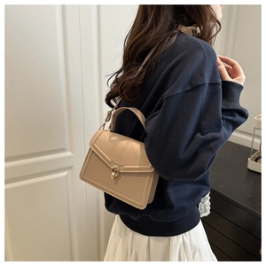 Detail of elegant beige crossbody bag featuring gold rotary lock and smooth leather texture