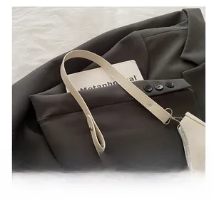 Détail du sac sous le bras en forme de croissant blanc cassé avec papillon en métal
