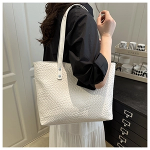 Close-up of white woven texture on a large tote bag with silver rivet hardware details