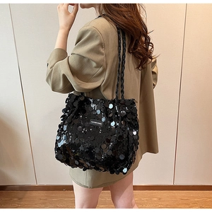 Close-up of black sequin tote bag with woven shoulder strap and fashion brand label