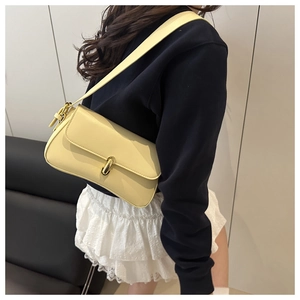 Detailed side view of a light yellow leather underarm bag with a gold oval metal lock