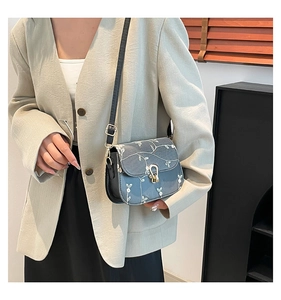 Detailed embroidery of white flowers on a blue-grey leather small crossbody bag
