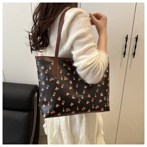 Sac fourre-tout vintage à imprimé cerises avec lanières brunes porté à l'épaule