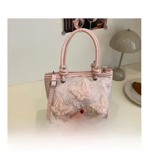Détail du sac seau en dentelle rose avec broderies papillons 3D et boucles en métal argent