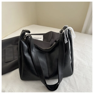 Detail of black faux leather tote bag featuring a white lace bow and smooth texture