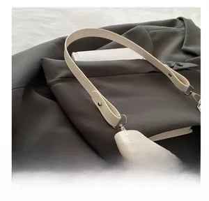 Gros plan sur la texture cuir blanc et la boucle argentée de la bandoulière du sac lune