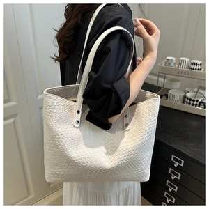 Detail of white woven tote bag texture with slim straps and metallic rivets on model