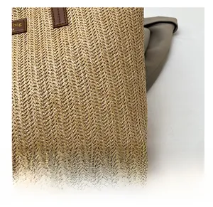 Gros plan sur la texture en paille tressée et l'anse en cuir marron d'un sac cabas