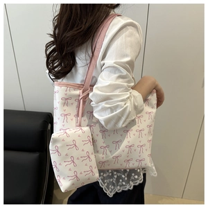Détail d'un grand sac cabas à imprimé nœud avec pochette assortie porté par un modèle