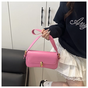 Detailed view of pink leather underarm bag with gold turn-lock and wide shoulder strap