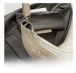 Détail de la fermeture éclair argentée et du sac croissant en cuir PU blanc crème grainé