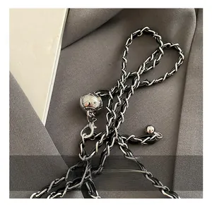 Detail of adjustable silver quilted metal ball and leather chain strap on a black handbag