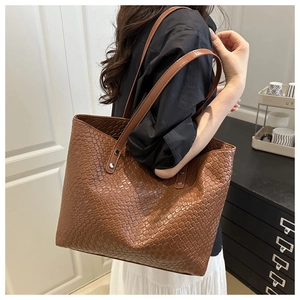 Detail of dark brown woven texture tote bag with slim shoulder straps and silver rivets