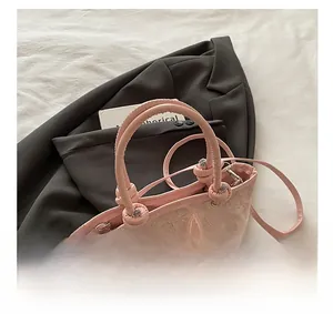 Détail de sac à main en dentelle rose avec appliques papillons 3D et poignées à nœuds