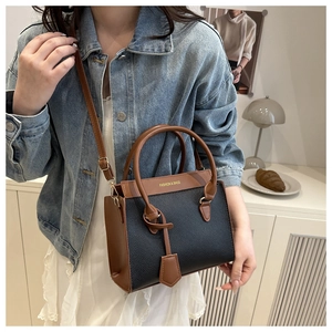 Detailed shot of two-tone crossbody bag with black lychee texture and brown strap