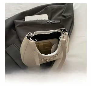 Vue détaillée du sac à bandoulière crème montrant l'intérieur spacieux et la boucle papillon