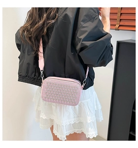Detail view of pink rhinestone camera bag with silver studs and wide nylon shoulder strap