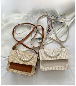 Detail of straw crossbody bags with pearl handles in brown and cream white tones