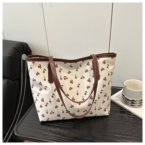 Détail du sac cabas imprimé cerises avec poignées et bordures en cuir marron foncé