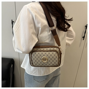 Brown vintage pattern crossbody bag with golden M-logo and wide fabric strap shown on model