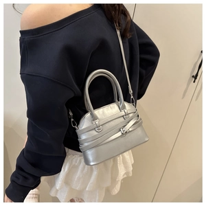 Silver shell handbag with crossover strap detail shown on a model for daily styling