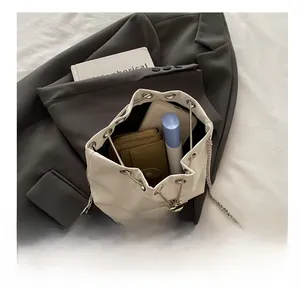 Interior view showing capacity of white bucket bag with chain strap and essentials