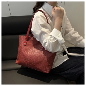 Close-up of red woven tote bag with silver rivets and long shoulder straps for women