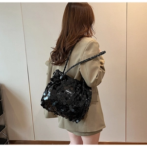 Detailed shot of black sequin tote bag with woven shoulder straps and logo patch