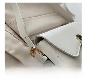 Detail of adjustable gold buckle on elegant white leather shoulder bag with fine texture