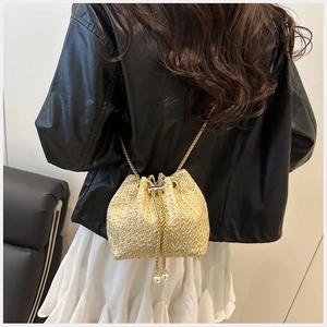 Detail of woven straw bucket bag with gold chain strap and pearl drawstring tassels