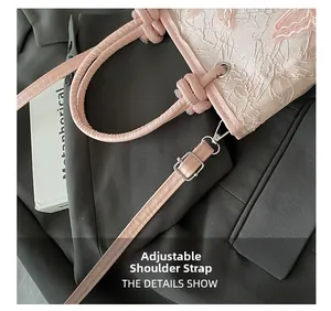 Détail de la bandoulière réglable en cuir rose et broderie en dentelle délicate