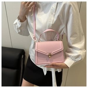Mannequin portant un sac à main structuré en cuir rose pâle avec fermoir rotatif doré