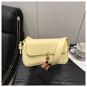 Detail of light yellow leather shoulder bag featuring a sleek golden metal clasp