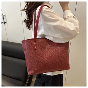 Detailed side view of deep red woven faux leather tote bag with slim shoulder straps