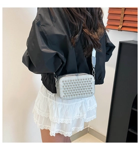 Detail of silver crossbody bag with studs and wide shoulder strap on model