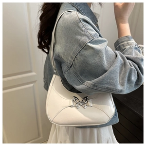 Détail du sac hobo en cuir verni blanc avec boucle papillon argentée sur le modèle