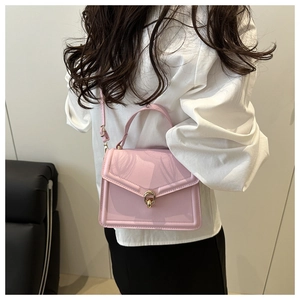 Detailed view of glossy pink crossbody bag with quilted texture and gold swivel lock