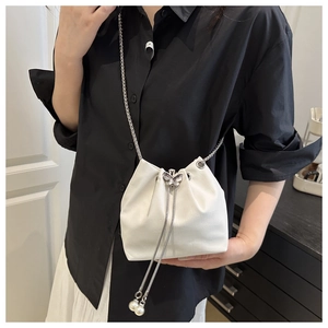 Detail of white crocodile pattern bucket bag with silver chain and butterfly pendant