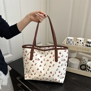 White cherry print tote bag with brown leather straps and spacious interior for daily use