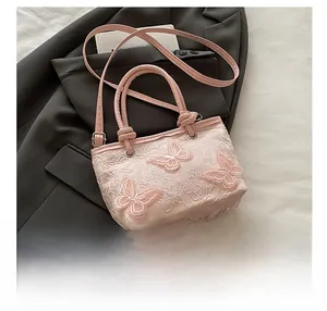 Détail de broderie de papillons 3D sur un sac seau en dentelle rose avec bandoulière