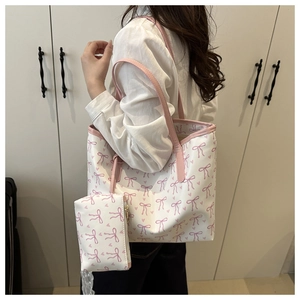 Detail of white tote bag featuring pink bow and heart prints with matching small pouch
