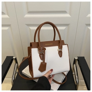 Detail of color-block tote bag featuring white lychee texture and brown smooth leather accents