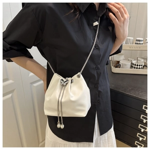 Detail of white pleated bucket bag with silver butterfly charm and chain strap
