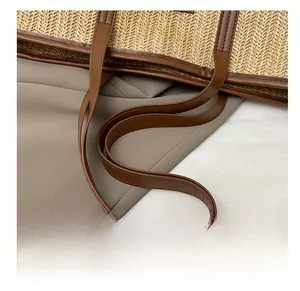 Détail des bandoulières en cuir marron sur un grand sac cabas en paille tressée beige